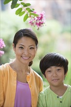 Portrait of smiling Asian mother and son near flowers