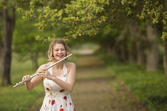 Caucasian teenage girl playing flute in park