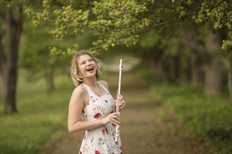 Caucasian teenage girl holding flute in park and laughing
