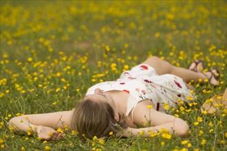 Caucasian teenage girl laying in field of flowers