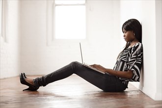 African woman using laptop on floor of empty room