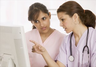 Two nurses talking in front of computer