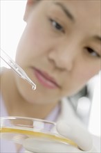 Close up of woman with eye dropper and petri dish