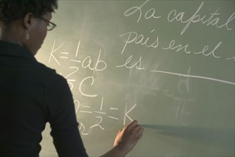 Rear view of woman writing on chalkboard