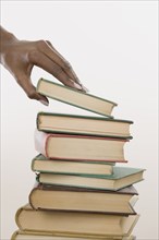 Close up of hands picking up book off stack