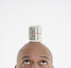 Man with roll of dollar bills on head
