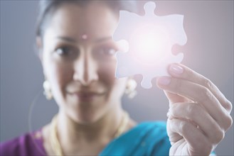 Woman in traditional Indian dress holding a puzzle piece