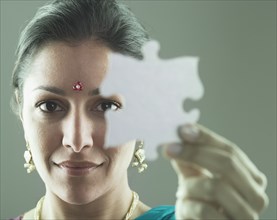 Woman in traditional Indian dress holding a puzzle piece