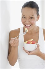 Portrait of woman eating bowl of fruit