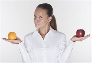 Portrait of woman balancing orange and apple in hands