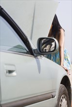 Woman looking under hood of car