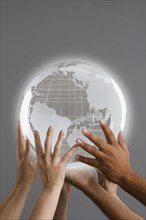 Close up of group of hands holding globe