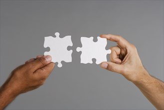 Close up of two hands holding puzzle pieces