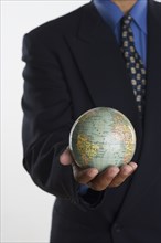 Mid section of businessman holding globe in hand