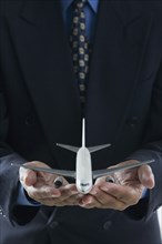 Close up of businessman's hands holding toy airplane