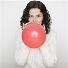 Portrait of woman blowing up balloon