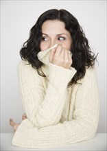 Portrait of woman covering mouth with sweater