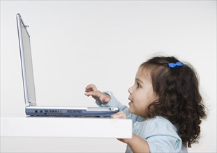 Young girl playing with laptop computer