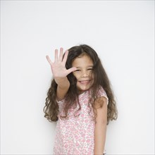 Portrait of young girl holding hand up in front of her