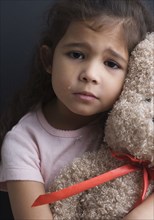 Portrait of girl crying and hugging teddy bear