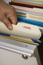 Close up of African male hand selecting confidential file from drawer