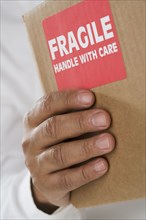 Close up of male hand holding package with fragile sticker