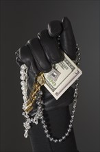 Close up of gloved hand with money and jewels