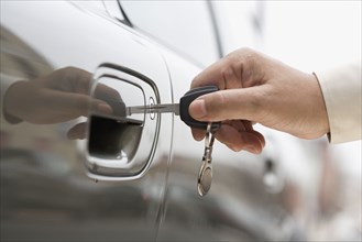 Close up of man's hand unlocking car door with key