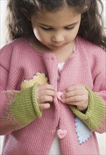 Young Hispanic girl buttoning sweater