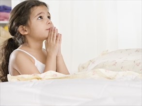 Young Hispanic girl saying bedtime prayers