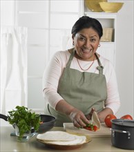 Senior Hispanic woman preparing food in kitchen