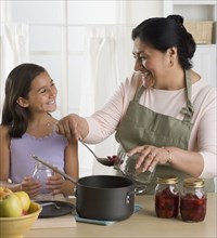 Hispanic grandmother and granddaughter preparing food in kitchen