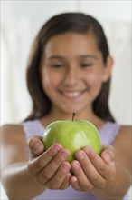Hispanic girl holding apple in outstretched hands