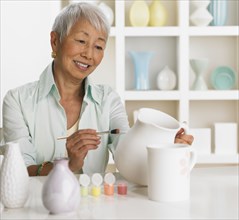 Senior Asian woman painting pottery
