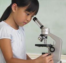 Young Asian girl looking through microscope