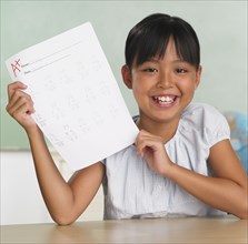 Asian girl holding up school paper with A+