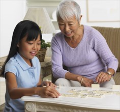 Asian grandmother and granddaughter playing dominoes