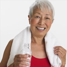 Studio shot of senior Asian woman with water and towel