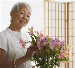 Senior Asian woman arranging flowers indoors