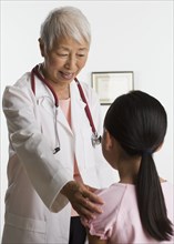 Senior Asian female doctor talking to young patient