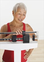 Senior Asian woman adjusting scale