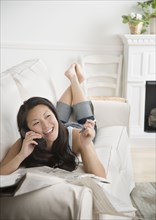 Young Asian woman using telephone on sofa