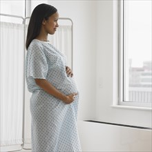 Pregnant African woman in hospital looking out window