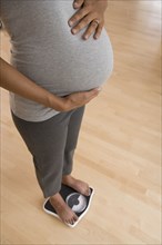 Pregnant African woman standing on scale