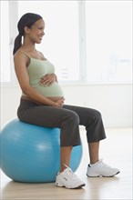 Pregnant African woman sitting on exercise ball