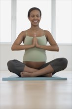 Pregnant African woman practicing yoga
