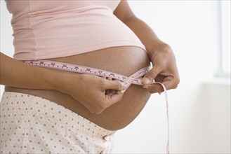 Pregnant African woman measuring belly