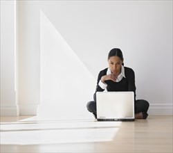 African businesswoman on floor looking at laptop