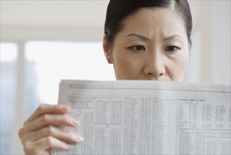 Middle-aged Asian woman reading newspaper