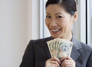 Middle-aged Asian businesswoman holding yen banknotes